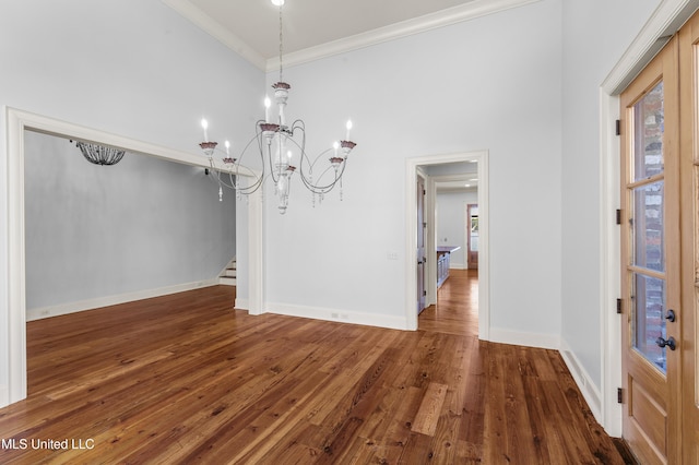 unfurnished dining area featuring a chandelier, a high ceiling, dark hardwood / wood-style flooring, and ornamental molding