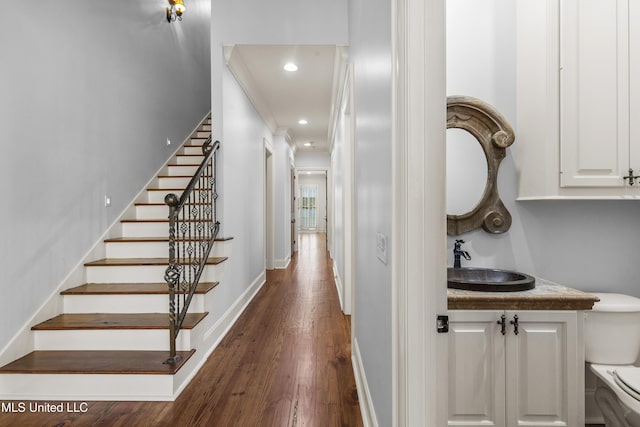 stairway featuring sink, ornamental molding, and hardwood / wood-style flooring