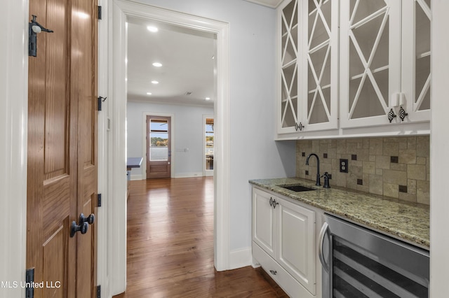 bar featuring dark hardwood / wood-style flooring, light stone counters, beverage cooler, crown molding, and white cabinets