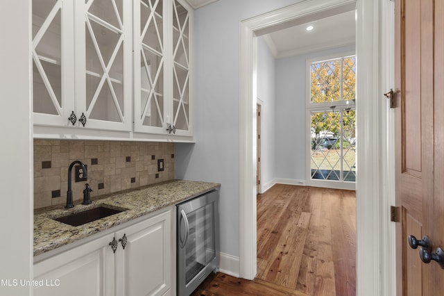 bar with white cabinetry, sink, beverage cooler, dark hardwood / wood-style floors, and crown molding