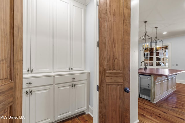 bar featuring beverage cooler, sink, pendant lighting, dark hardwood / wood-style floors, and white cabinetry