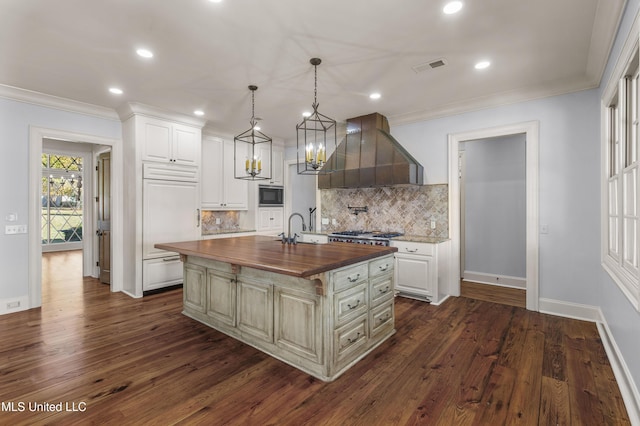 kitchen with ventilation hood, dark hardwood / wood-style floors, a kitchen island with sink, and wooden counters