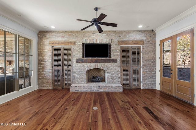 unfurnished living room featuring french doors, a brick fireplace, brick wall, ceiling fan, and hardwood / wood-style floors