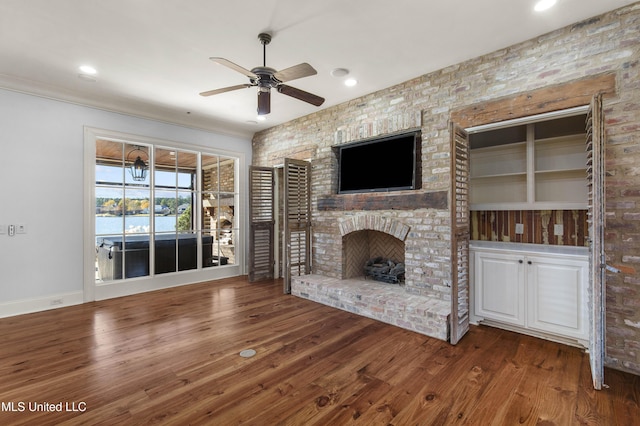 unfurnished living room featuring wood-type flooring, a brick fireplace, and ceiling fan