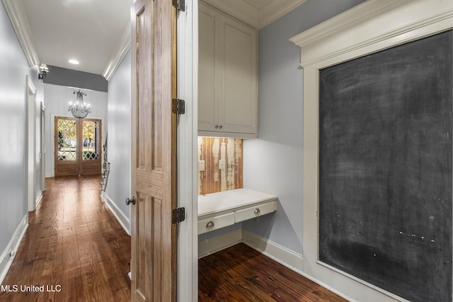 hallway featuring dark hardwood / wood-style flooring, an inviting chandelier, french doors, and ornamental molding