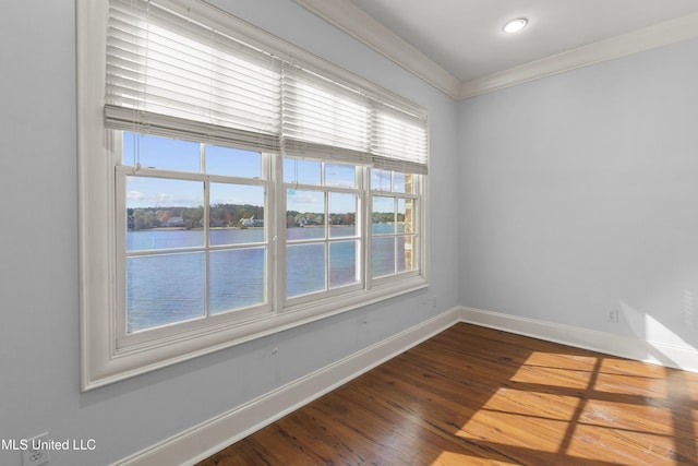 empty room featuring a water view, ornamental molding, and wood-type flooring