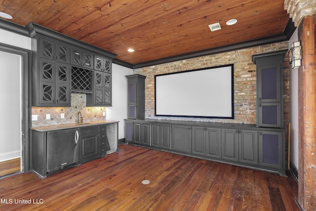 cinema room featuring ornamental molding, dark hardwood / wood-style floors, wet bar, and wooden ceiling