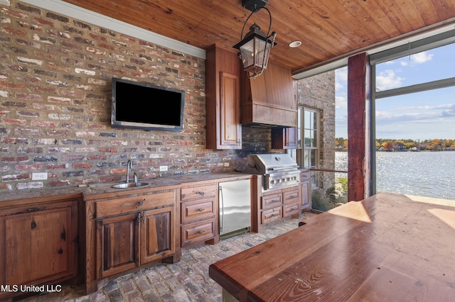 kitchen featuring sink, tasteful backsplash, brick wall, stainless steel fridge, and decorative light fixtures