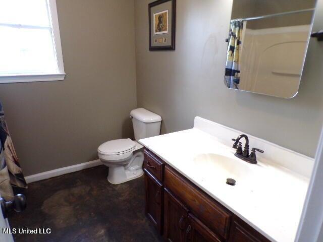 bathroom featuring toilet, vanity, a shower with shower curtain, and baseboards