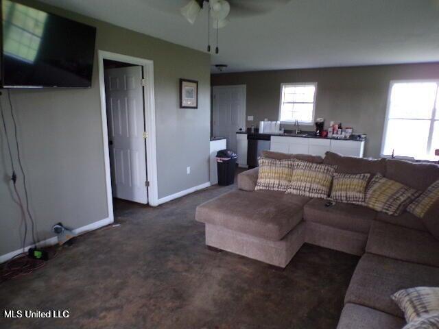 living room with baseboards, carpet floors, and ceiling fan