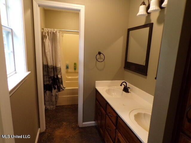 bathroom with double vanity, shower / tub combo, and a sink