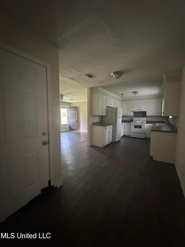 1010 Deryll St, Jackson, MS 39212 - kitchen featuring white appliances, dark countertops, a sink, white cabinetry, and dark wood-style flooring