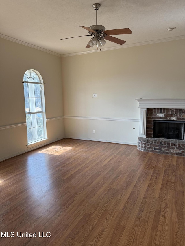 unfurnished living room featuring ceiling fan, a fireplace, ornamental molding, and wood-type flooring