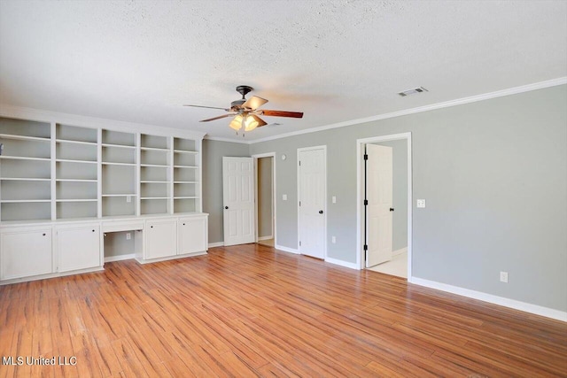 interior space featuring a textured ceiling, built in desk, light wood-type flooring, and ceiling fan