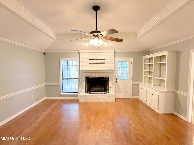 unfurnished living room featuring a wealth of natural light, crown molding, a fireplace, and light wood-type flooring