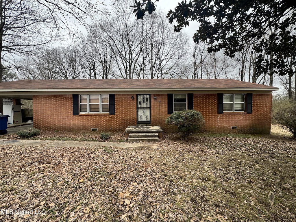 ranch-style house featuring a shingled roof, a carport, brick siding, and crawl space