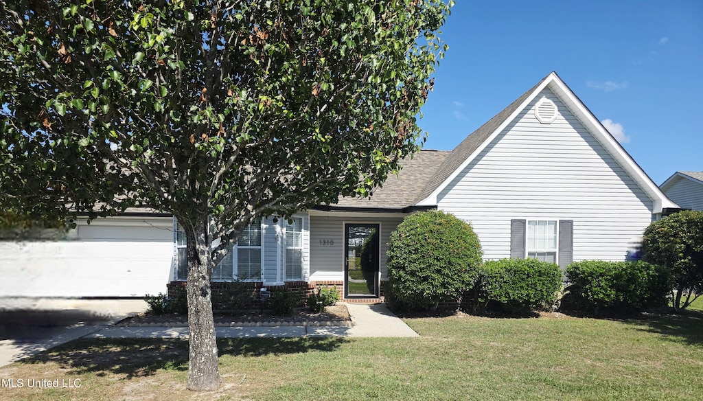 obstructed view of property with a shingled roof, an attached garage, and a front yard