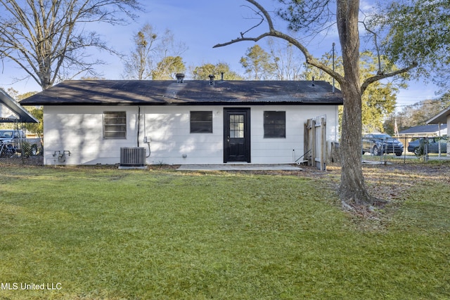 rear view of house featuring cooling unit and a yard