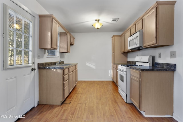 kitchen with light brown cabinetry, sink, white appliances, and light hardwood / wood-style floors