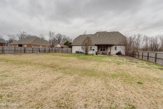 rear view of property featuring brick siding, a fenced backyard, a lawn, and a patio