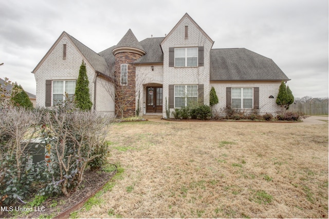 french country inspired facade featuring brick siding, a front lawn, and roof with shingles