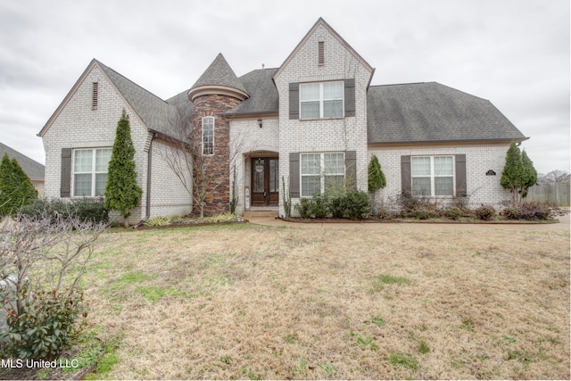 french provincial home featuring brick siding, a front lawn, and a shingled roof