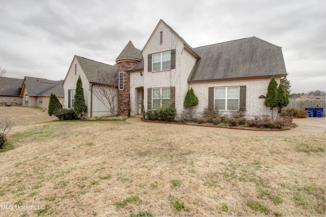 view of front of house featuring a front yard, brick siding, and roof with shingles