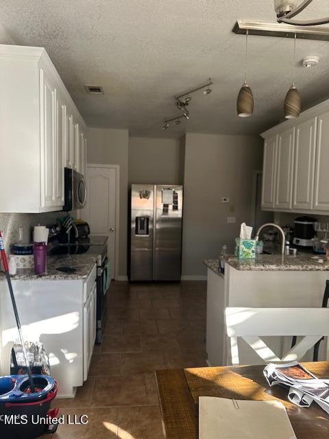 kitchen featuring light stone countertops, a textured ceiling, stainless steel appliances, and white cabinets