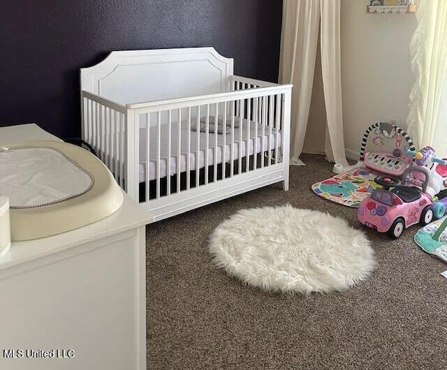 bedroom featuring a crib and dark colored carpet