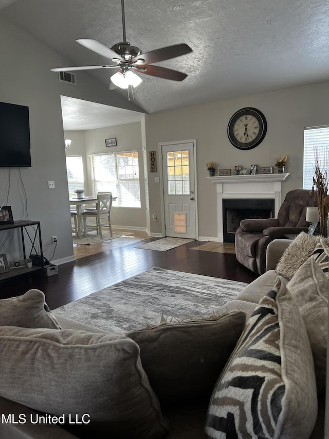 living room with vaulted ceiling, ceiling fan, hardwood / wood-style floors, and a textured ceiling