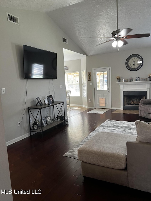 living room featuring dark hardwood / wood-style floors, ceiling fan, lofted ceiling, and a textured ceiling