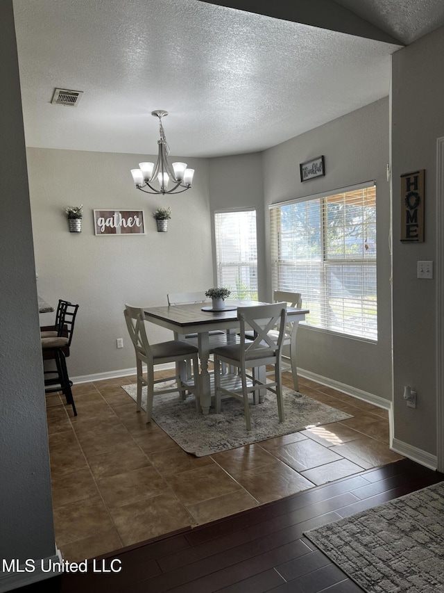 dining room with a textured ceiling and a notable chandelier