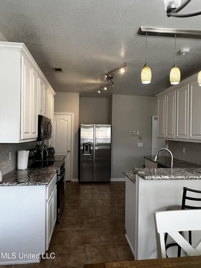 kitchen with electric range, hanging light fixtures, stainless steel fridge, dark stone counters, and white cabinets