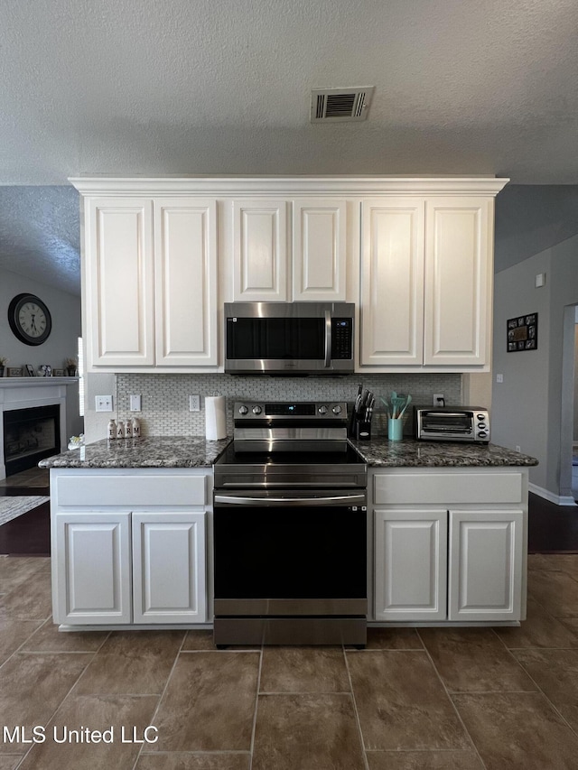 kitchen with white cabinets, stainless steel appliances, and a textured ceiling