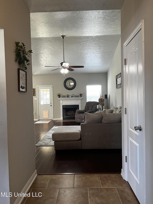 living room featuring a textured ceiling, ceiling fan, dark tile patterned floors, and lofted ceiling