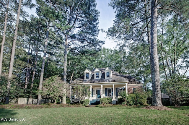 new england style home featuring a porch, a front yard, and fence