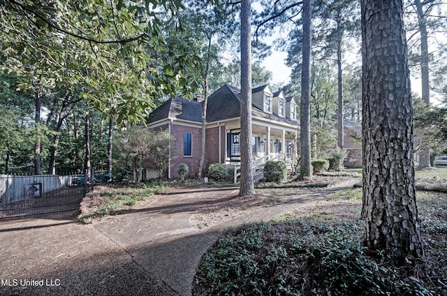 view of front of home with fence, a porch, and brick siding