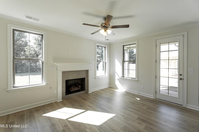 unfurnished living room with a wealth of natural light, a fireplace, wood-type flooring, and ceiling fan