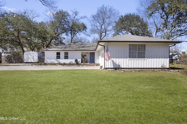 view of front facade with a shingled roof, a front lawn, and an outdoor structure