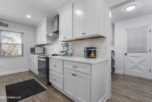 kitchen featuring stainless steel appliances, white cabinets, dark wood-type flooring, and wall chimney range hood