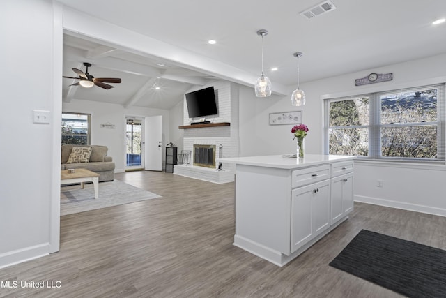 kitchen with lofted ceiling with beams, a fireplace, visible vents, white cabinetry, and open floor plan