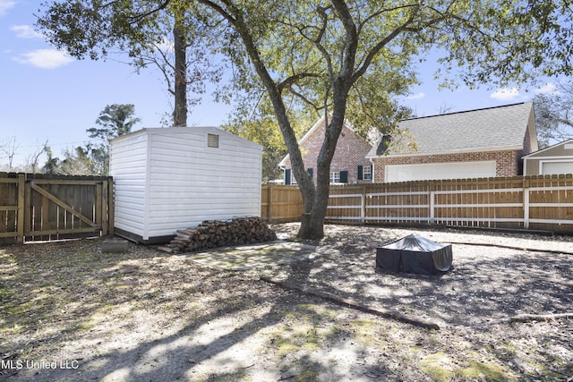 view of yard featuring an outbuilding, a storage unit, a fenced backyard, and a gate