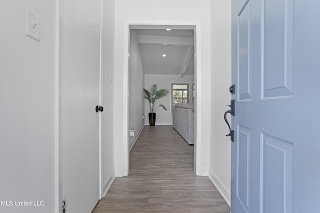 hallway with beamed ceiling, baseboards, and wood finished floors