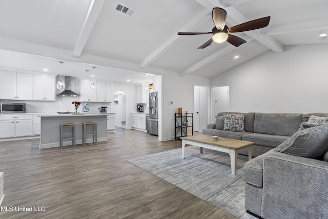 living room featuring lofted ceiling with beams, ceiling fan, wood finished floors, visible vents, and baseboards