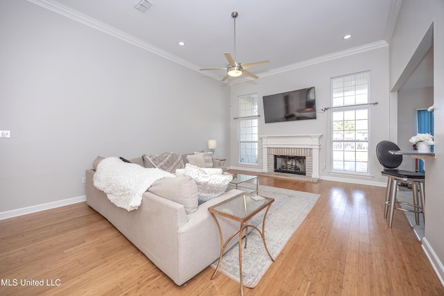 living room featuring crown molding, ceiling fan, a fireplace, and light hardwood / wood-style flooring