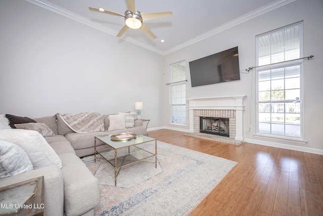 living room featuring crown molding, ceiling fan, a fireplace, and hardwood / wood-style flooring