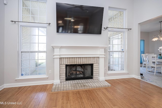 unfurnished living room featuring hardwood / wood-style floors, a fireplace, and a chandelier