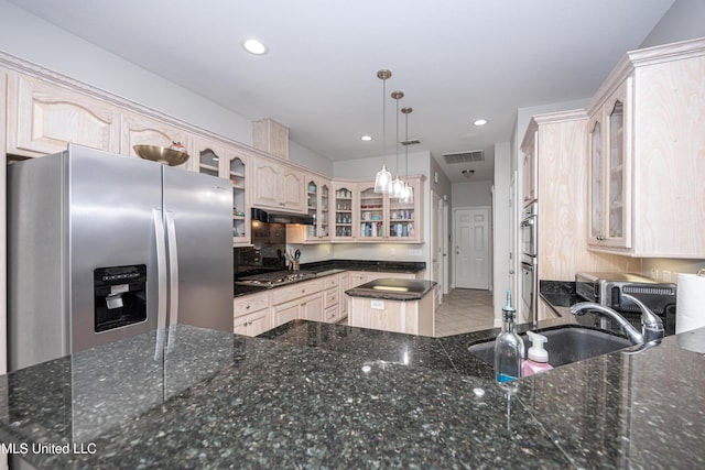 kitchen with stainless steel appliances, sink, dark stone counters, and decorative light fixtures