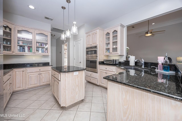 kitchen with a kitchen island, double oven, sink, light tile patterned floors, and light brown cabinets