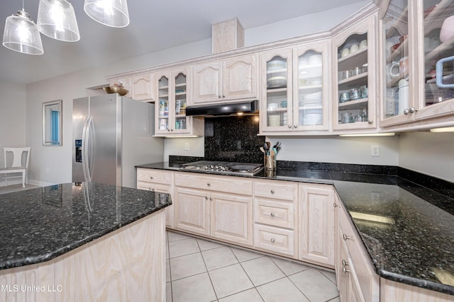 kitchen featuring stainless steel appliances, light tile patterned flooring, dark stone countertops, and pendant lighting